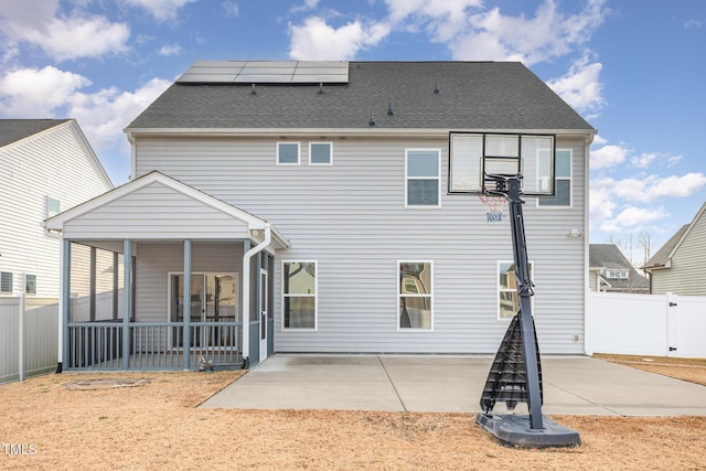 back of property with a sunroom, a patio, and solar panels