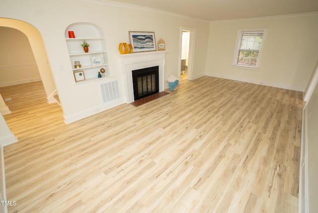 living room featuring built in shelves, ornamental molding, and light hardwood / wood-style flooring