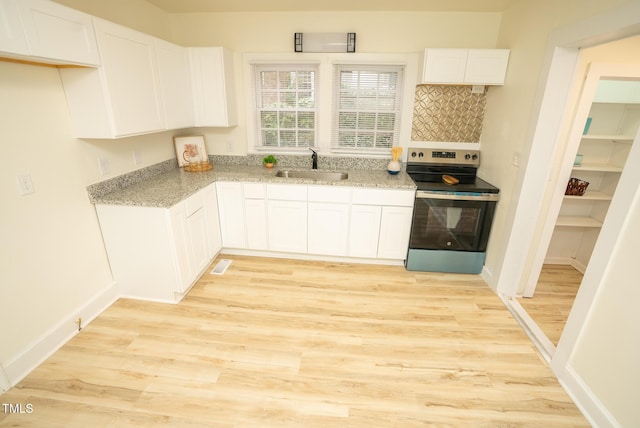 kitchen featuring tasteful backsplash, sink, light hardwood / wood-style flooring, white cabinetry, and stainless steel electric range