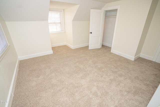 unfurnished bedroom featuring light colored carpet, vaulted ceiling, and a closet