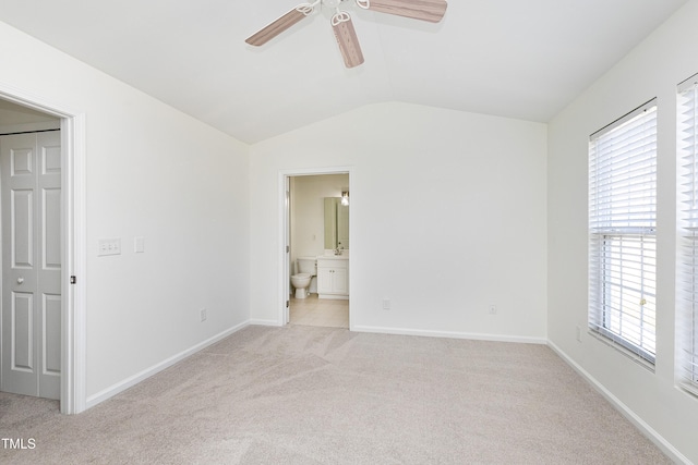 unfurnished bedroom with sink, ceiling fan, connected bathroom, vaulted ceiling, and light colored carpet