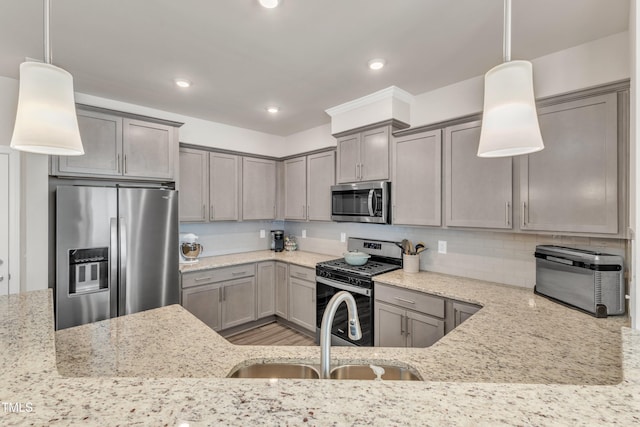 kitchen featuring appliances with stainless steel finishes, decorative light fixtures, light stone counters, and sink