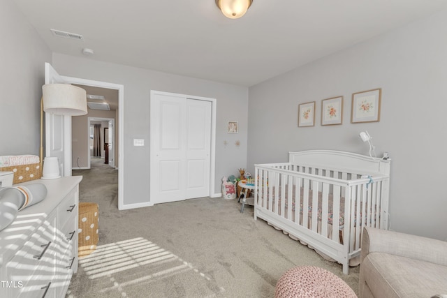 bedroom featuring a crib, light carpet, and a closet