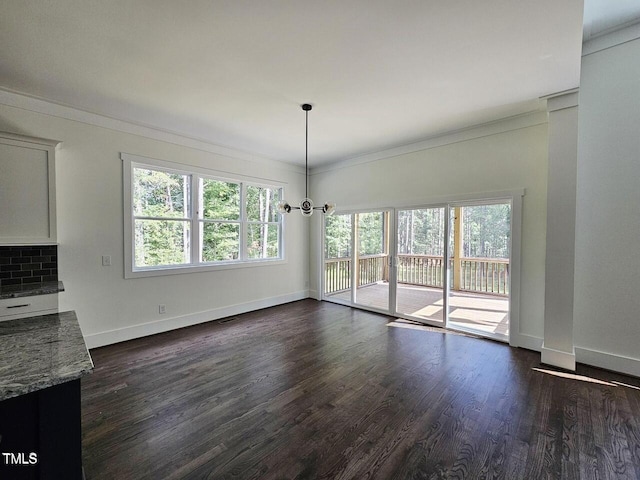 unfurnished dining area featuring crown molding, dark wood-type flooring, and an inviting chandelier