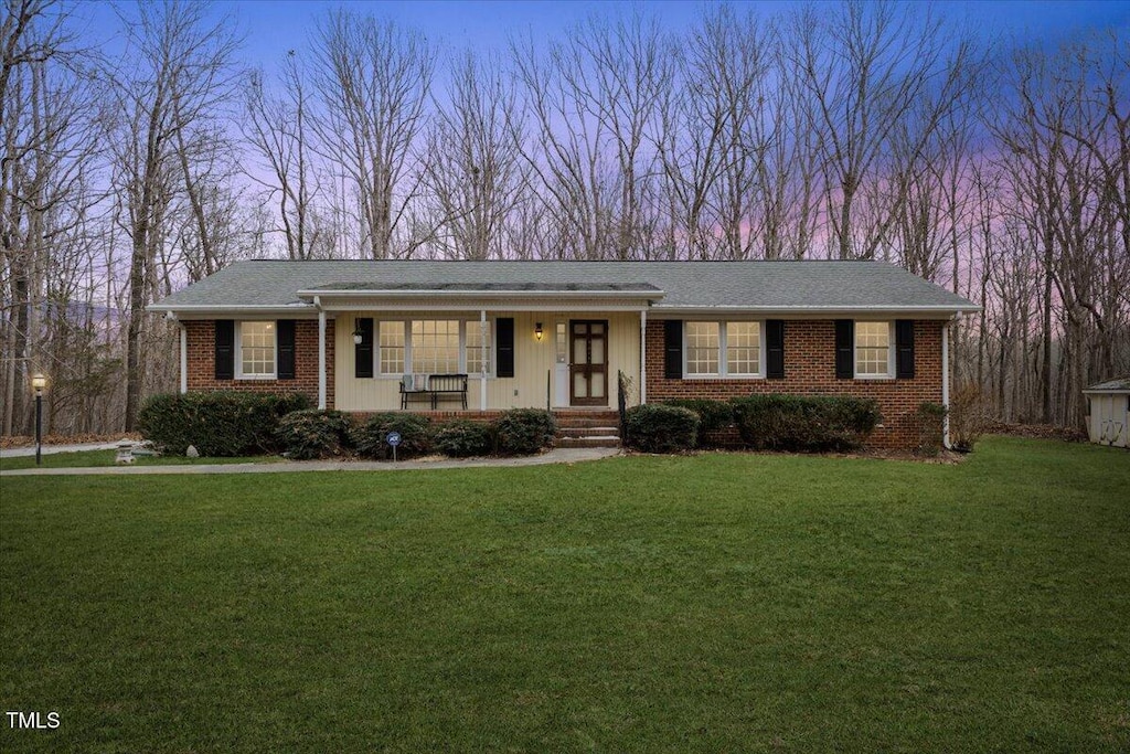 ranch-style house with a porch and a lawn