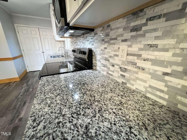 kitchen featuring light stone countertops, dark hardwood / wood-style flooring, ornamental molding, sink, and stainless steel range oven