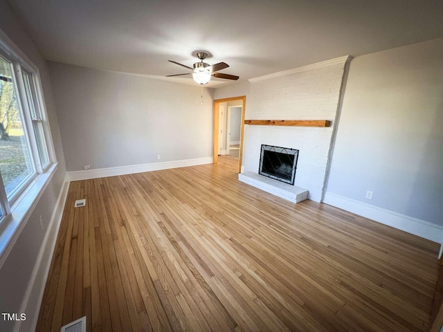 unfurnished living room with plenty of natural light, ceiling fan, light wood-type flooring, and a fireplace