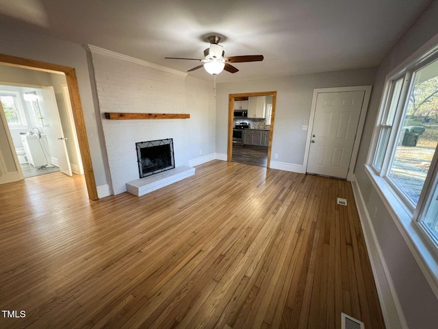 unfurnished living room with ceiling fan, light hardwood / wood-style flooring, and a brick fireplace