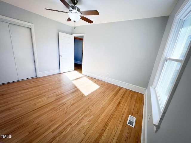 unfurnished bedroom with ceiling fan, a closet, and light hardwood / wood-style floors