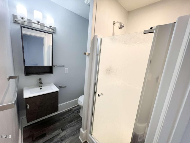 bathroom featuring wood-type flooring, vanity, toilet, and a shower with door