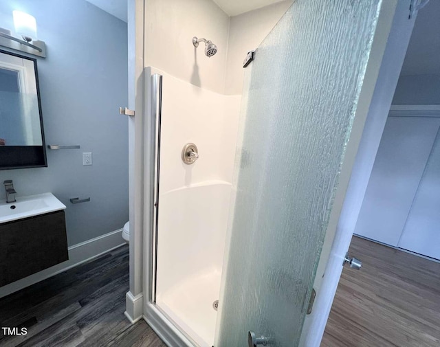 bathroom featuring hardwood / wood-style flooring, vanity, toilet, and walk in shower