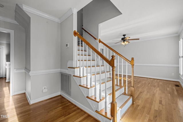 stairway with ceiling fan, crown molding, and hardwood / wood-style flooring