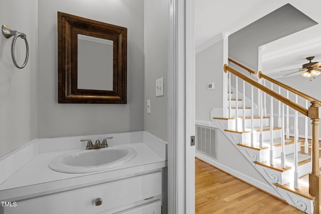 bathroom with ceiling fan, vanity, ornamental molding, and hardwood / wood-style flooring