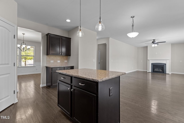 kitchen featuring a center island, hanging light fixtures, dark hardwood / wood-style floors, backsplash, and ceiling fan with notable chandelier