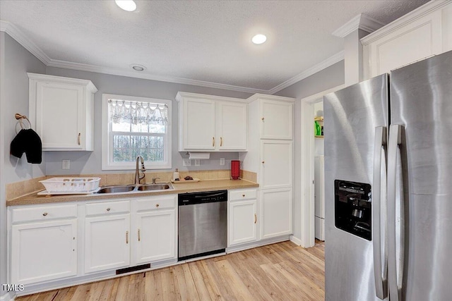 kitchen with sink, crown molding, appliances with stainless steel finishes, white cabinetry, and light hardwood / wood-style floors