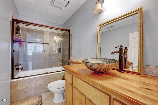 full bathroom with enclosed tub / shower combo, vanity, toilet, and a textured ceiling