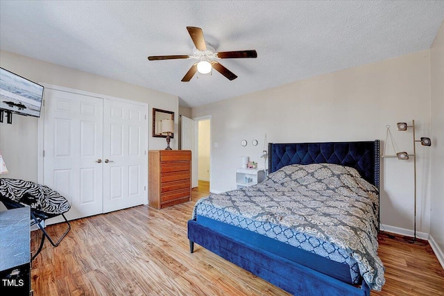 bedroom with hardwood / wood-style flooring, a textured ceiling, ceiling fan, and a closet