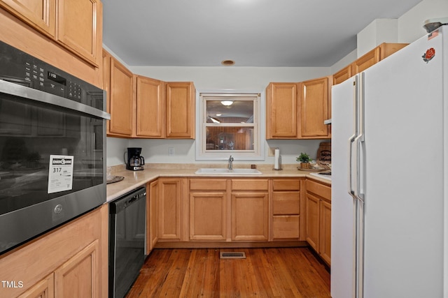 kitchen featuring stainless steel oven, white fridge, light hardwood / wood-style floors, black dishwasher, and sink