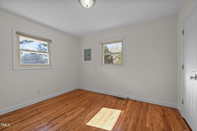 spare room with electric panel and wood-type flooring