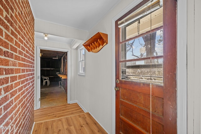 interior space with brick wall and light hardwood / wood-style flooring