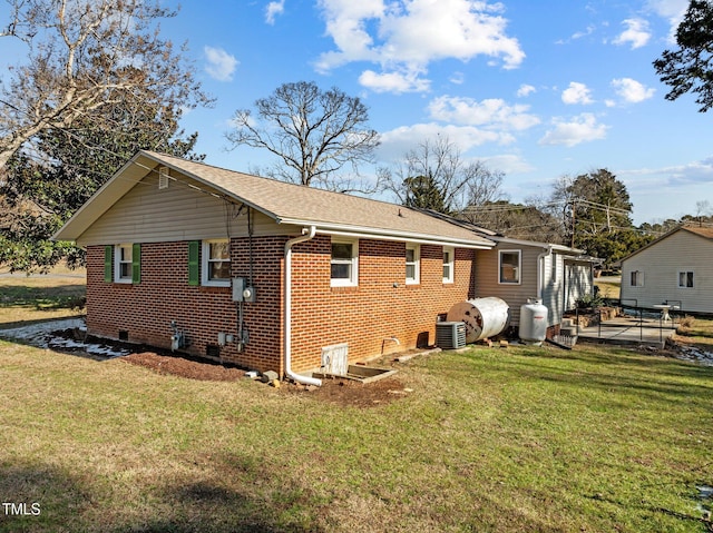 rear view of property featuring central air condition unit and a yard