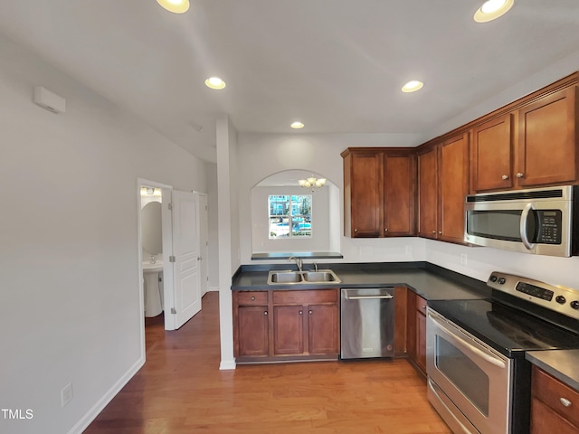 kitchen with sink, an inviting chandelier, light hardwood / wood-style flooring, and appliances with stainless steel finishes