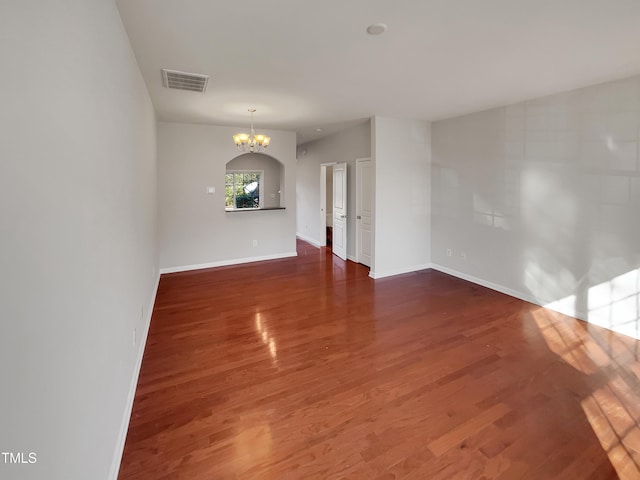 spare room with a chandelier and dark hardwood / wood-style floors