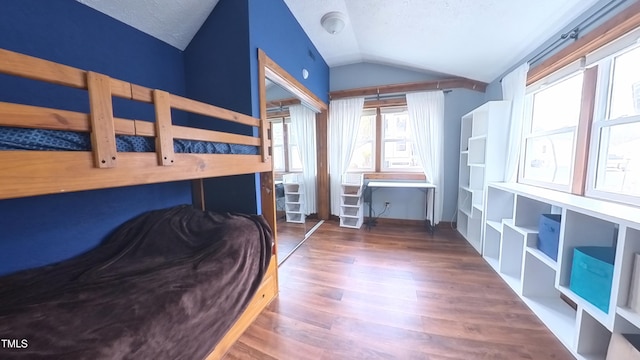 bedroom featuring hardwood / wood-style floors, a textured ceiling, and vaulted ceiling