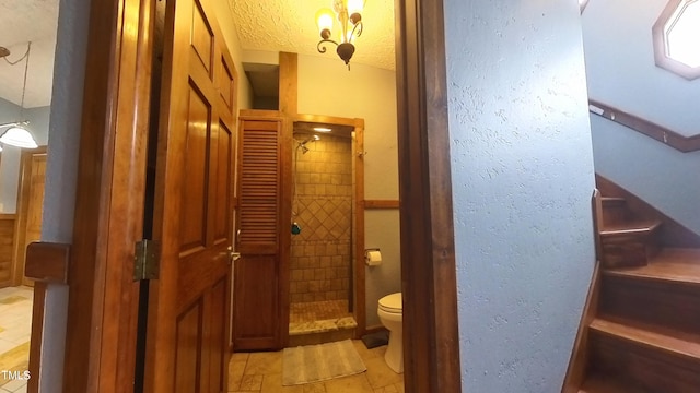 bathroom with tiled shower, a textured ceiling, and toilet