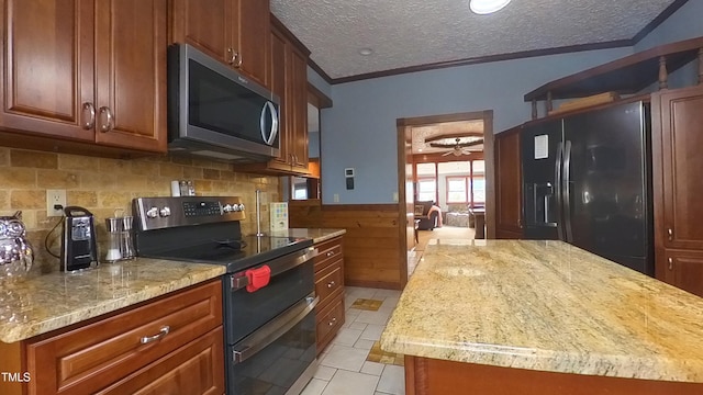 kitchen featuring a textured ceiling, crown molding, wooden walls, black appliances, and light tile patterned flooring