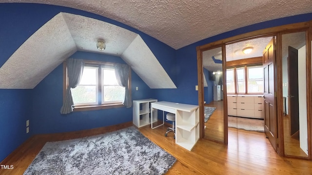 bonus room with a textured ceiling, hardwood / wood-style flooring, and lofted ceiling