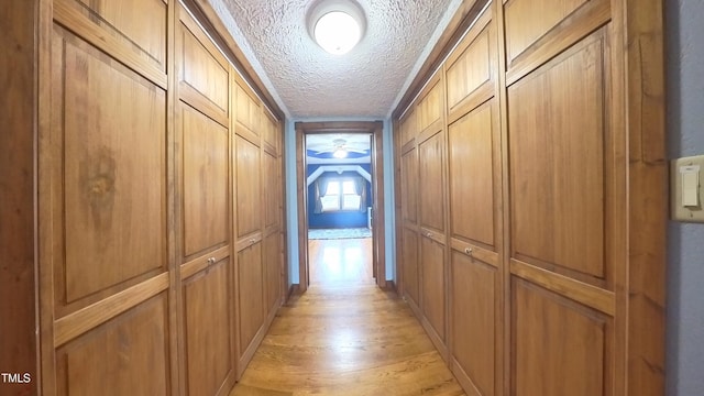 hallway featuring light wood-type flooring and a textured ceiling