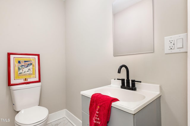 bathroom featuring toilet, marble finish floor, vanity, and baseboards