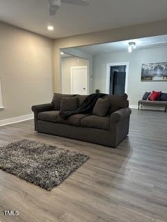 living room featuring a ceiling fan, baseboards, and wood finished floors