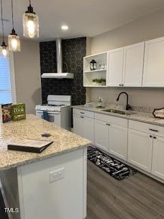 kitchen with white cabinets, light stone counters, range hood, white gas stove, and a sink