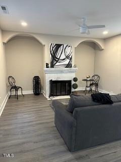 living room with a ceiling fan, a glass covered fireplace, baseboards, and wood finished floors