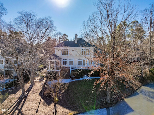 rear view of property featuring a deck with water view and a chimney