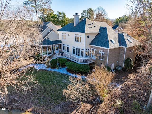 rear view of property featuring a deck, central AC unit, a sunroom, stairs, and a chimney