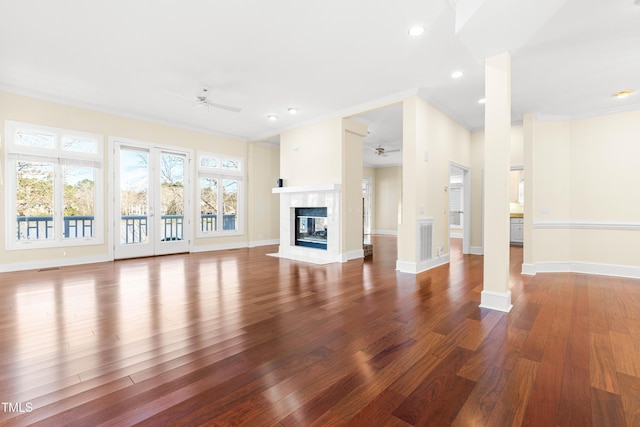 unfurnished living room featuring crown molding, a premium fireplace, a ceiling fan, wood finished floors, and baseboards