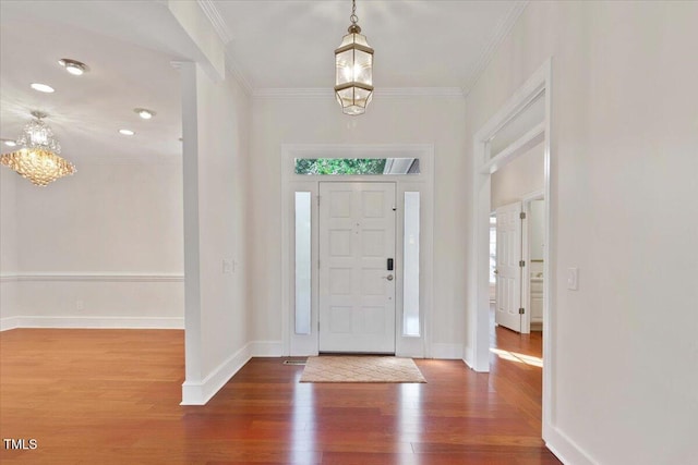 entryway with crown molding, a wealth of natural light, an inviting chandelier, wood finished floors, and baseboards