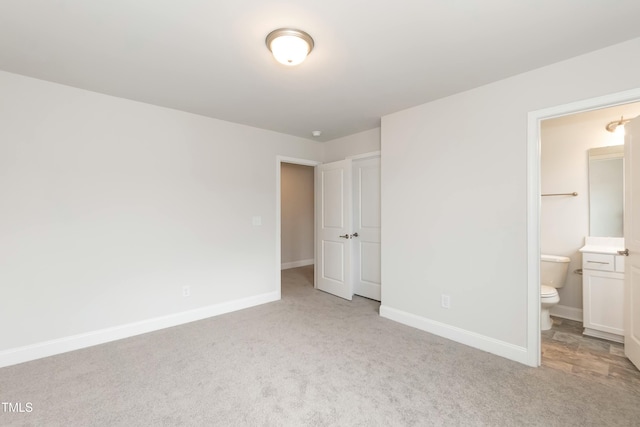 unfurnished bedroom with connected bathroom and light colored carpet