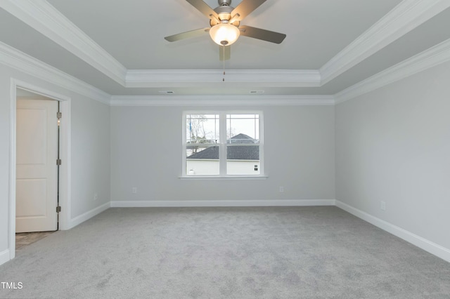 carpeted empty room featuring ceiling fan, ornamental molding, and a tray ceiling