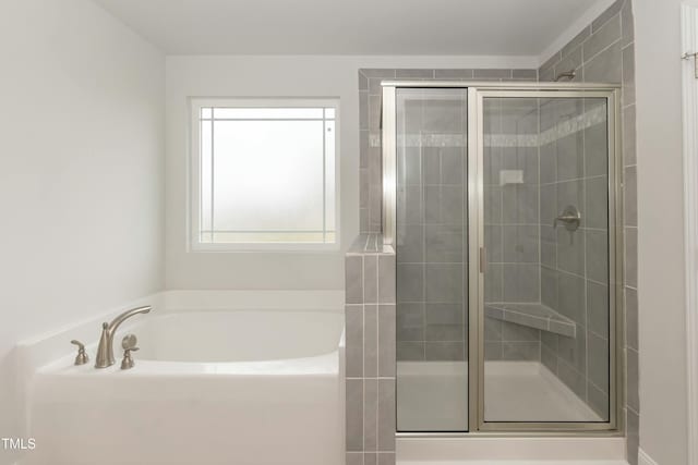 bathroom featuring plenty of natural light and independent shower and bath