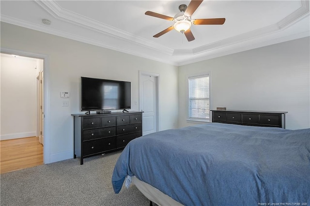 carpeted bedroom featuring a tray ceiling, ceiling fan, and crown molding