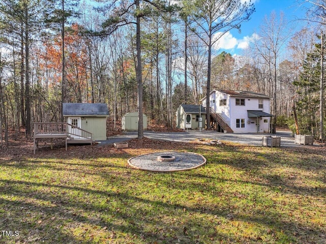 view of yard featuring a shed, an outdoor fire pit, and a wooden deck