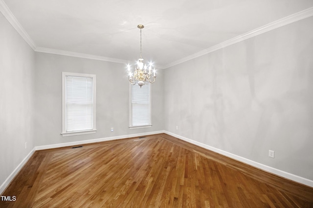 empty room with hardwood / wood-style floors, crown molding, and a notable chandelier