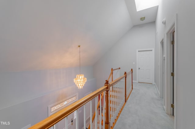 hallway with light carpet, a chandelier, and vaulted ceiling with skylight