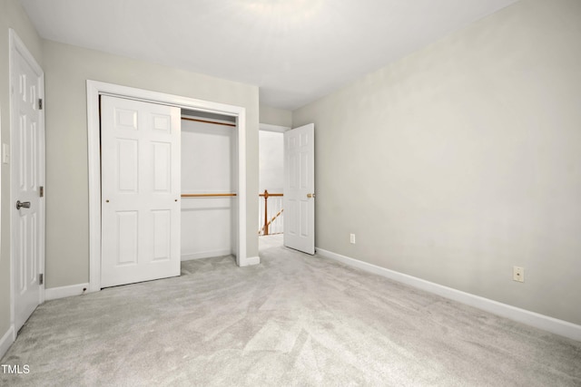 unfurnished bedroom with light colored carpet and a closet