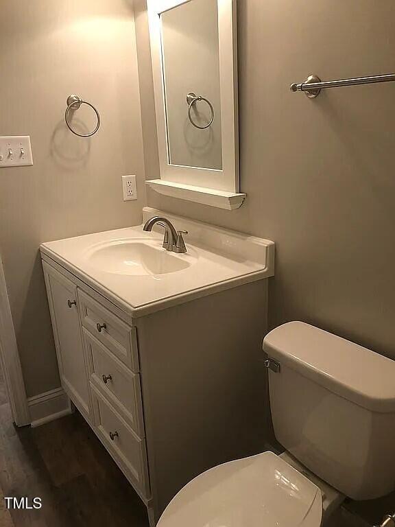 bathroom with wood-type flooring, vanity, and toilet