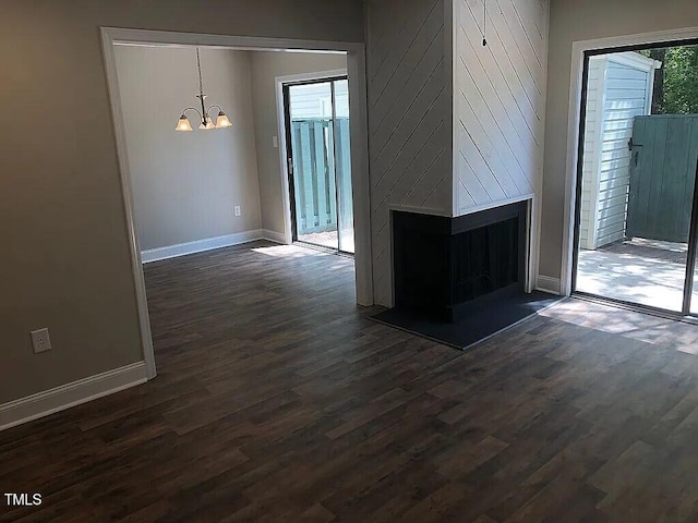 unfurnished living room with a fireplace, dark hardwood / wood-style floors, and a notable chandelier